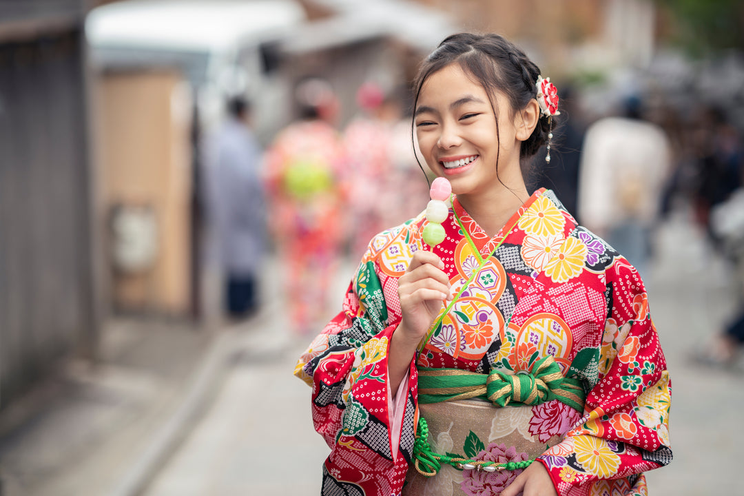 A girl in traditional kimono dress enjoying dango on the street